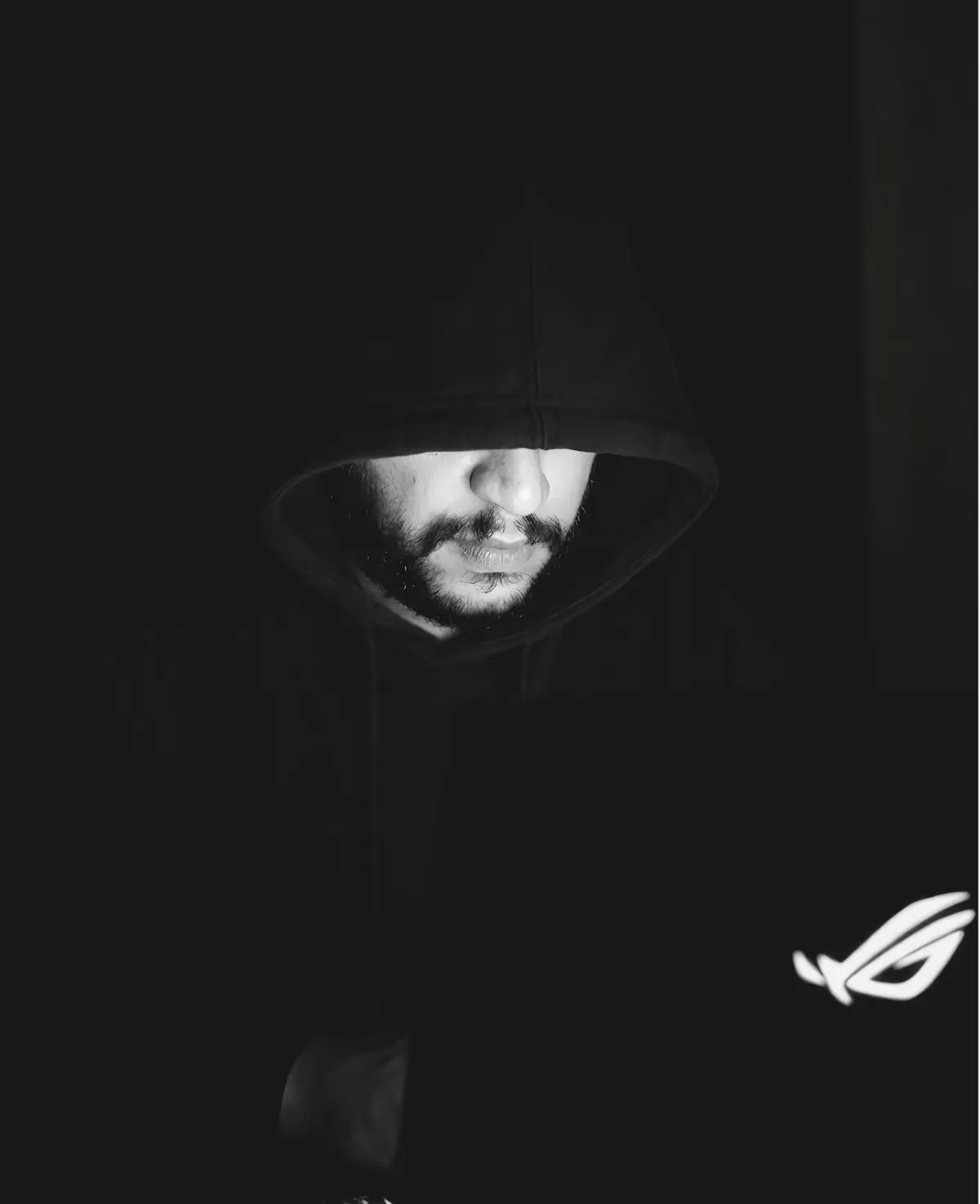 Person in a hoodie using a laptop in a dark room